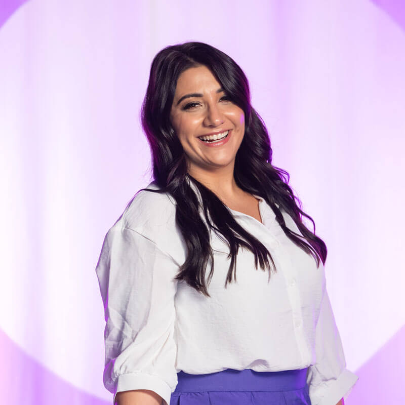 Ajla Crnalic Moderatorin für Events, in Lila Bluse steht vor einem Publikum und redet.
